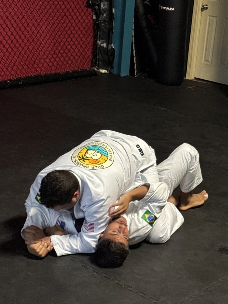 Two adults training Brazilian Jiu-Jitsu on the mats at Gulf Shores BJJ